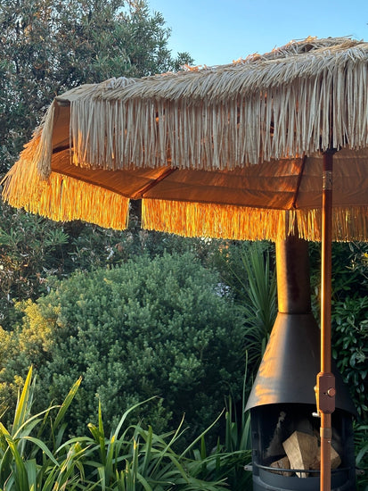 Hula 275cm Market Umbrella with raffia thatch canopy and crank lift system in outdoor garden setting
