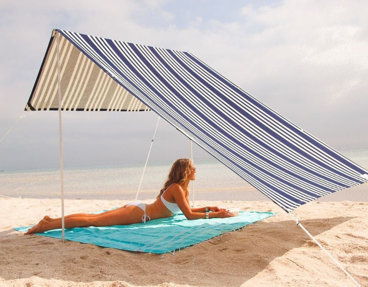 Lovin Summer Sombrilla shade tent with blue and white stripes on sandy beach