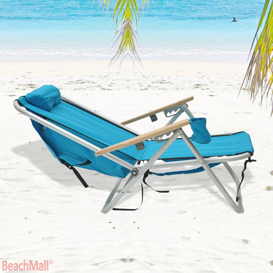 Beachkit Wearever Backpack Chair in turquoise on sandy beach with palm leaves and ocean background